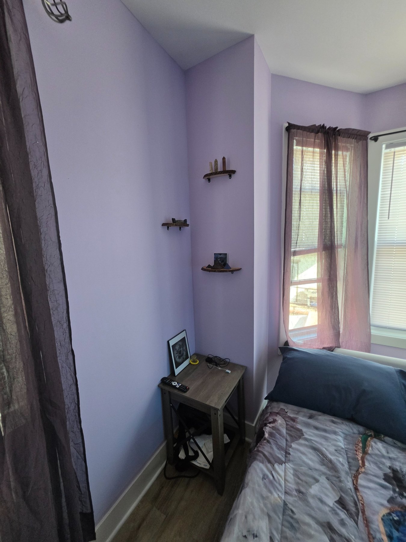 Small wall shelves displaying crystals beside the bed