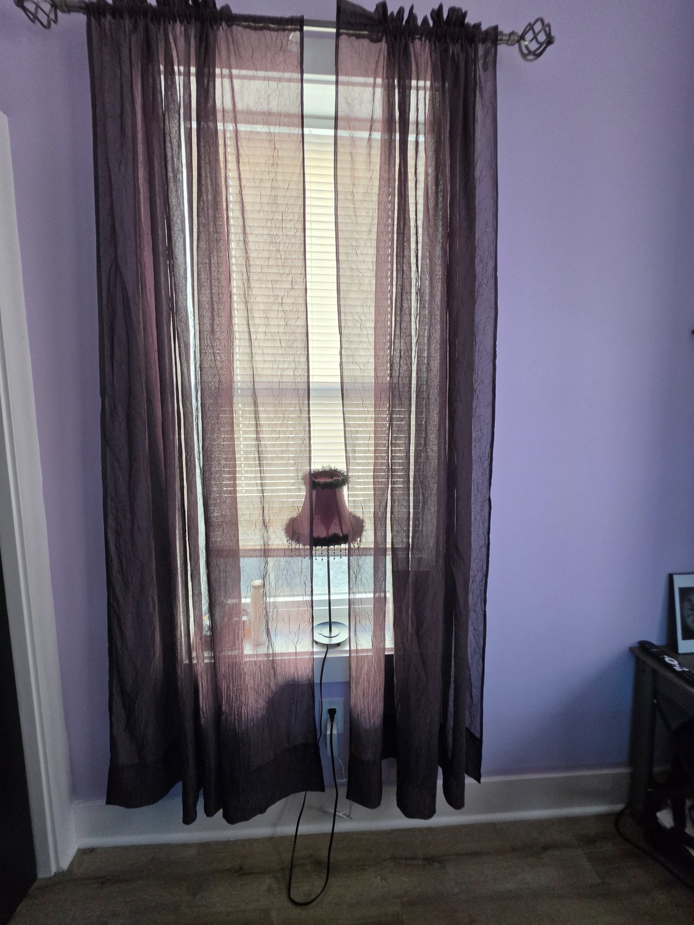 Dark sheer curtains framing a small lamp in the window