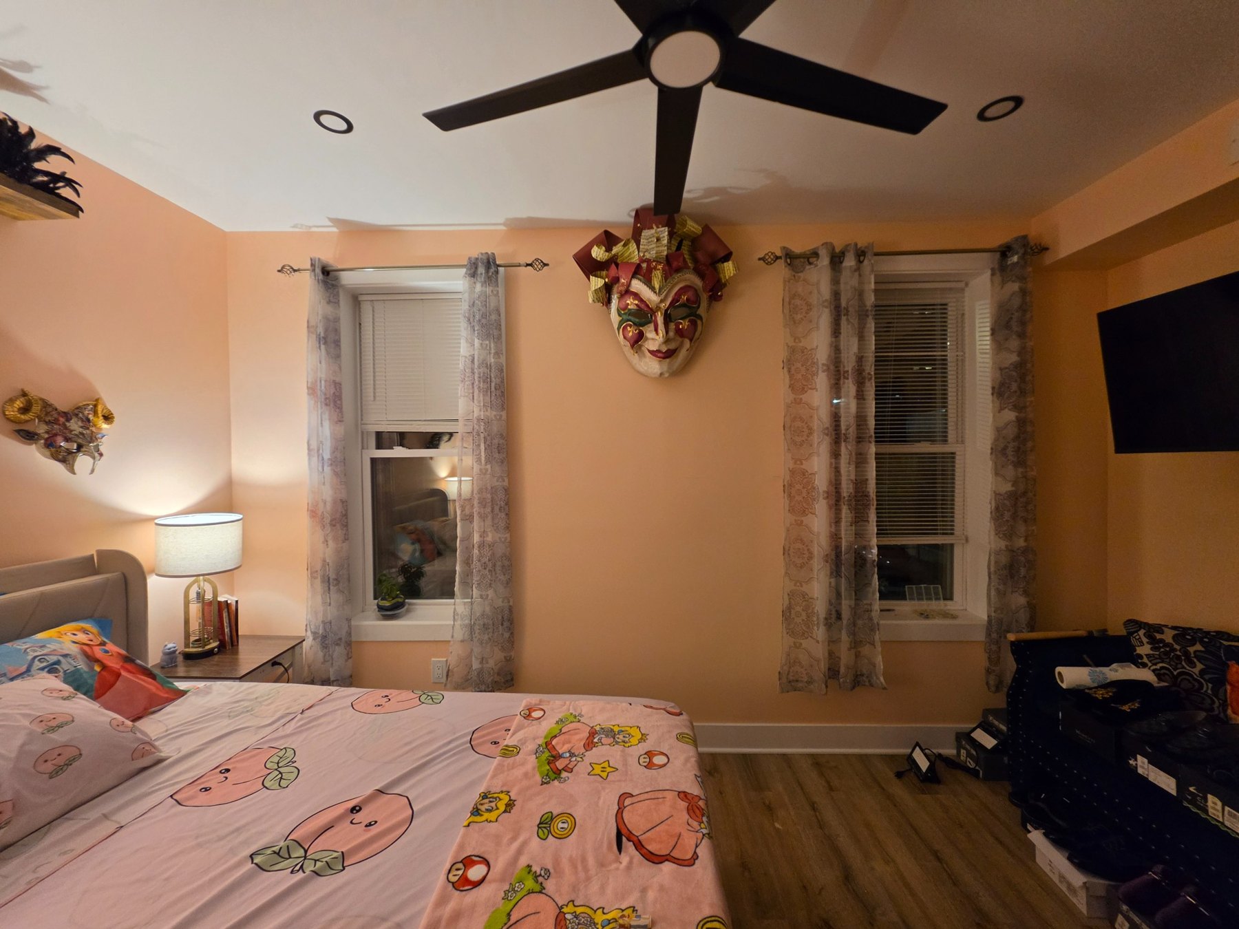 Wide view of the peach room with windows, ceiling fan and large central mask